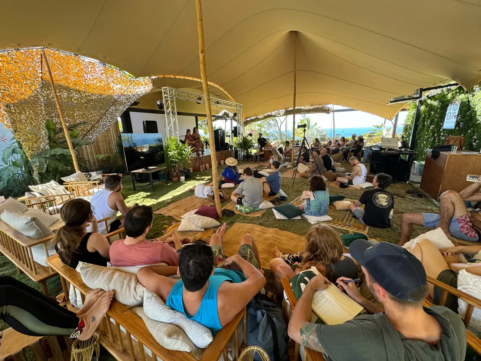 Audience seated in a large tent facing a speaker