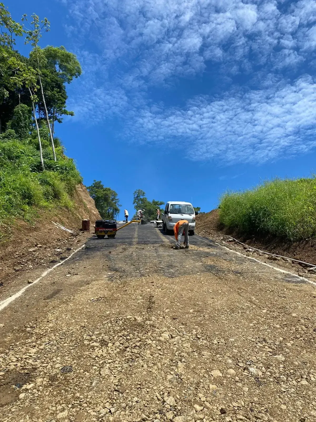 Road being graded up a slope under blue sky
