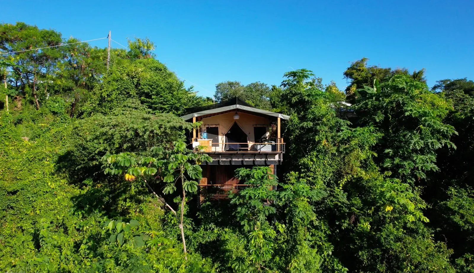 Raised wooden cabin with a deck above the jungle canopy