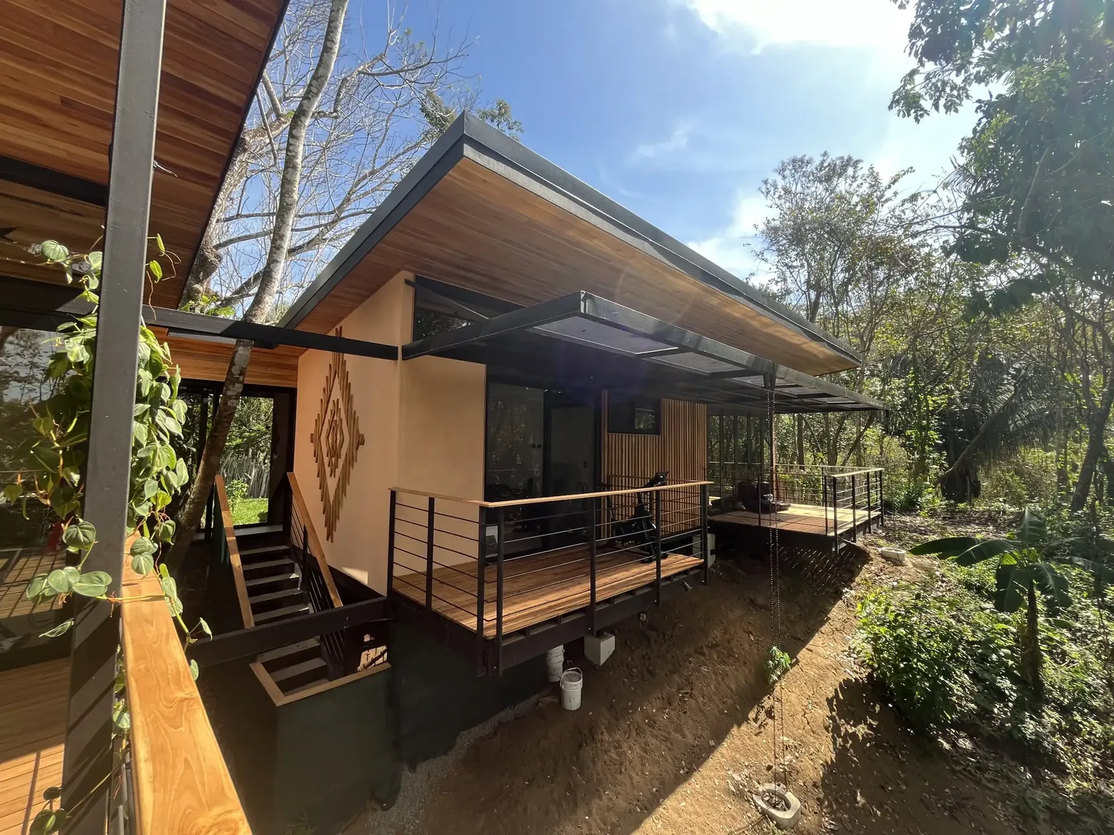 Single-storey wood and plaster house with a raised deck among dry-forest trees